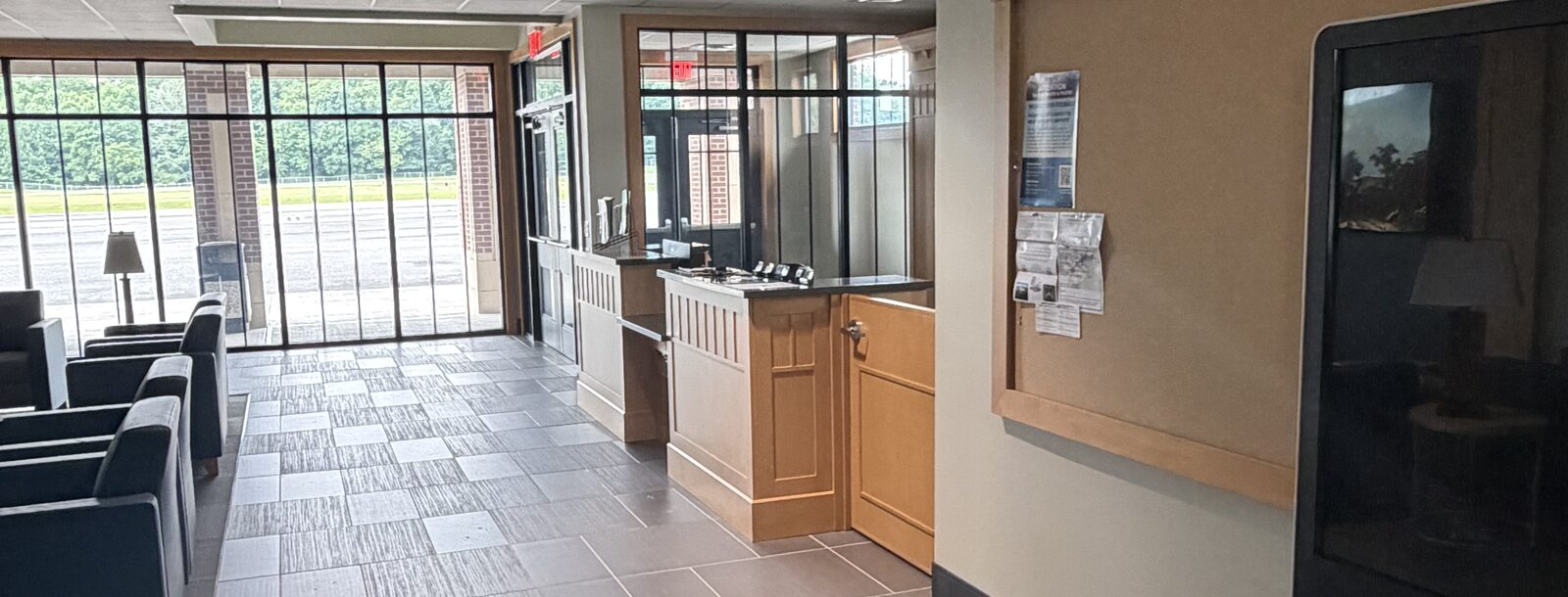 The terminal lobby at Russell County Airport, looking past lounge seating and the reception counter to a glass wall onto the ramp
