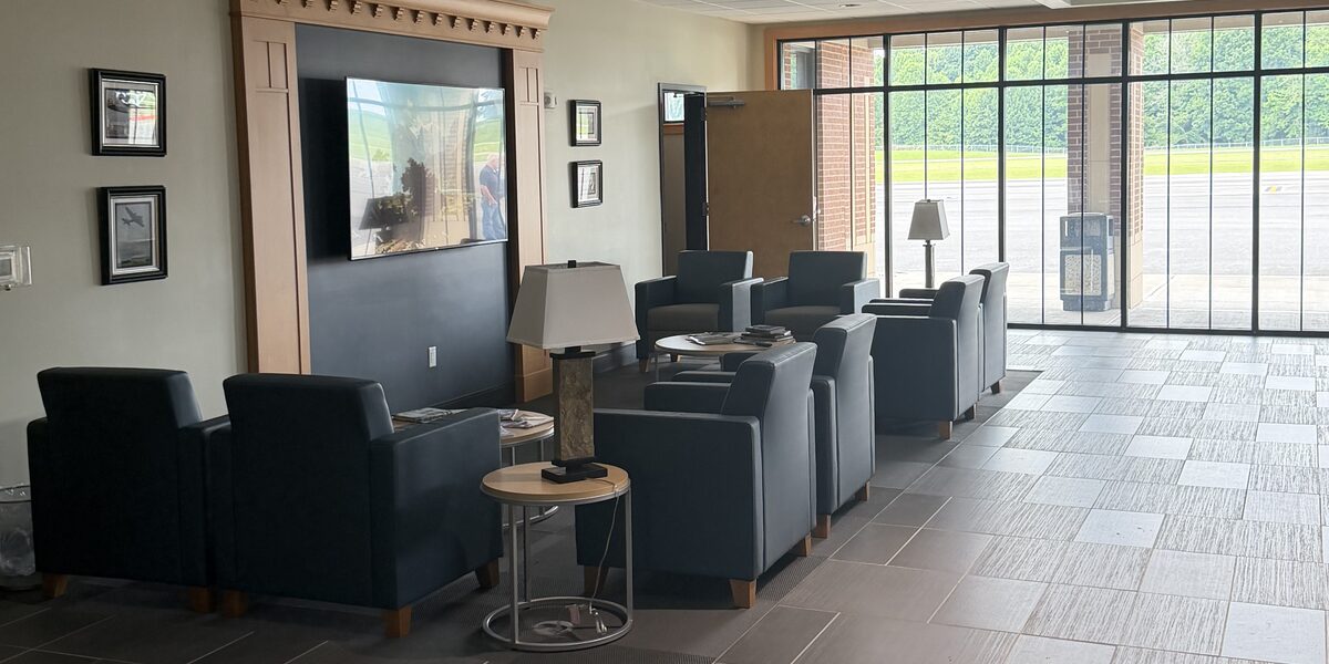 The pilot lounge, with leather armchairs, framed aviation prints, a wall-mounted television and floor-to-ceiling windows onto the ramp